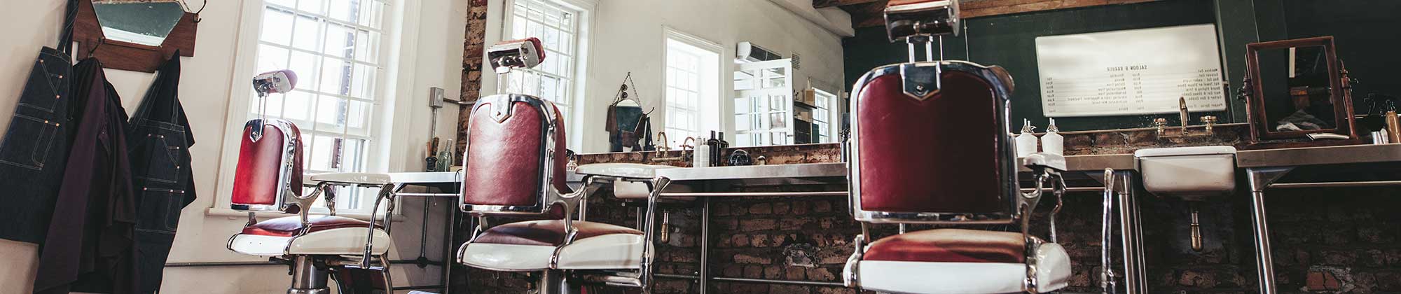 a row of barber chairs in front of a mirror