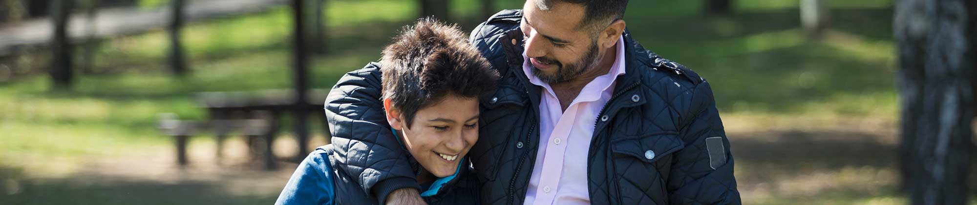 man walking with his son in a park, both of them hugging each other